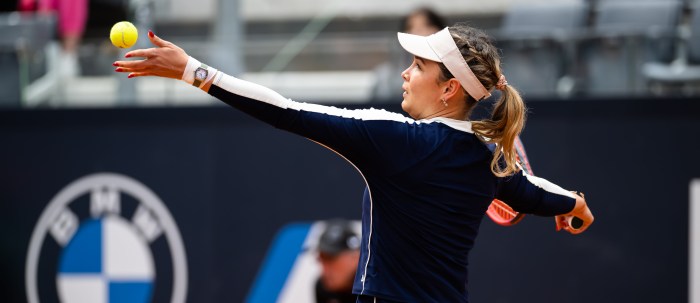 A tennis player tosses a tennis ball